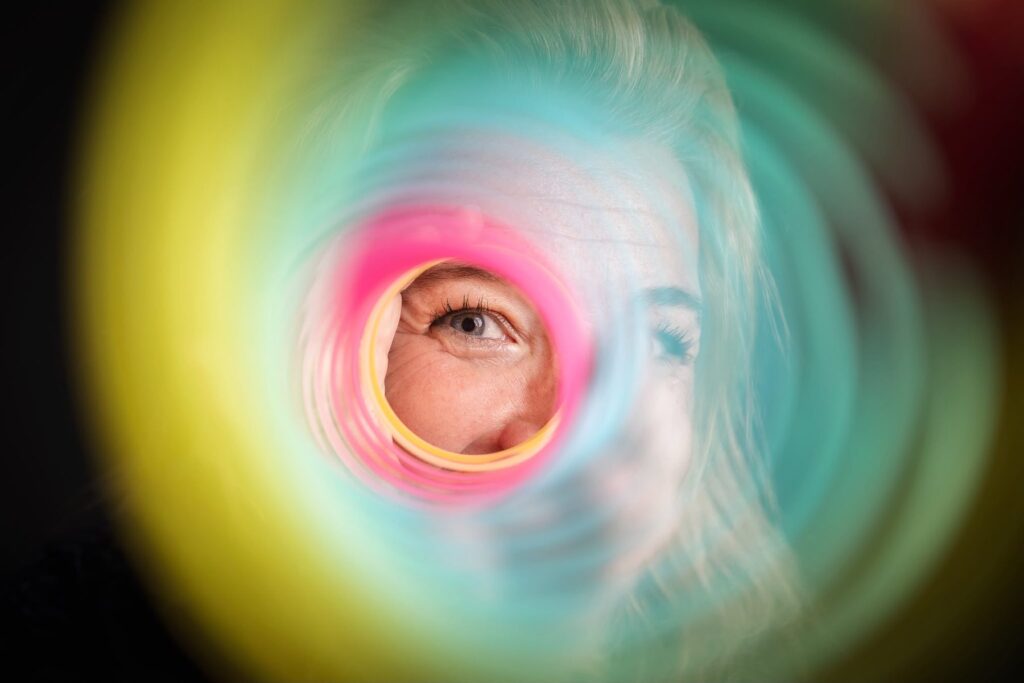 Een oog kijkt door een kleurrijke regenboogveer