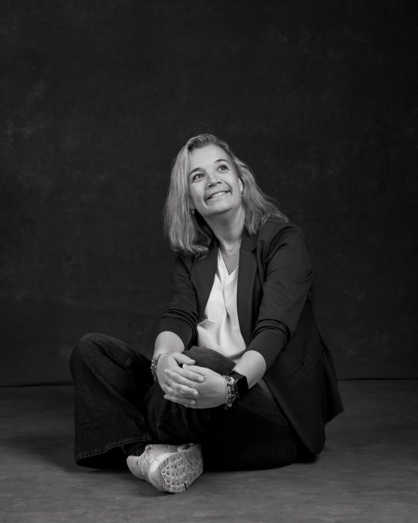 Agnes zittend op de grond, lachend omhoog kijkend